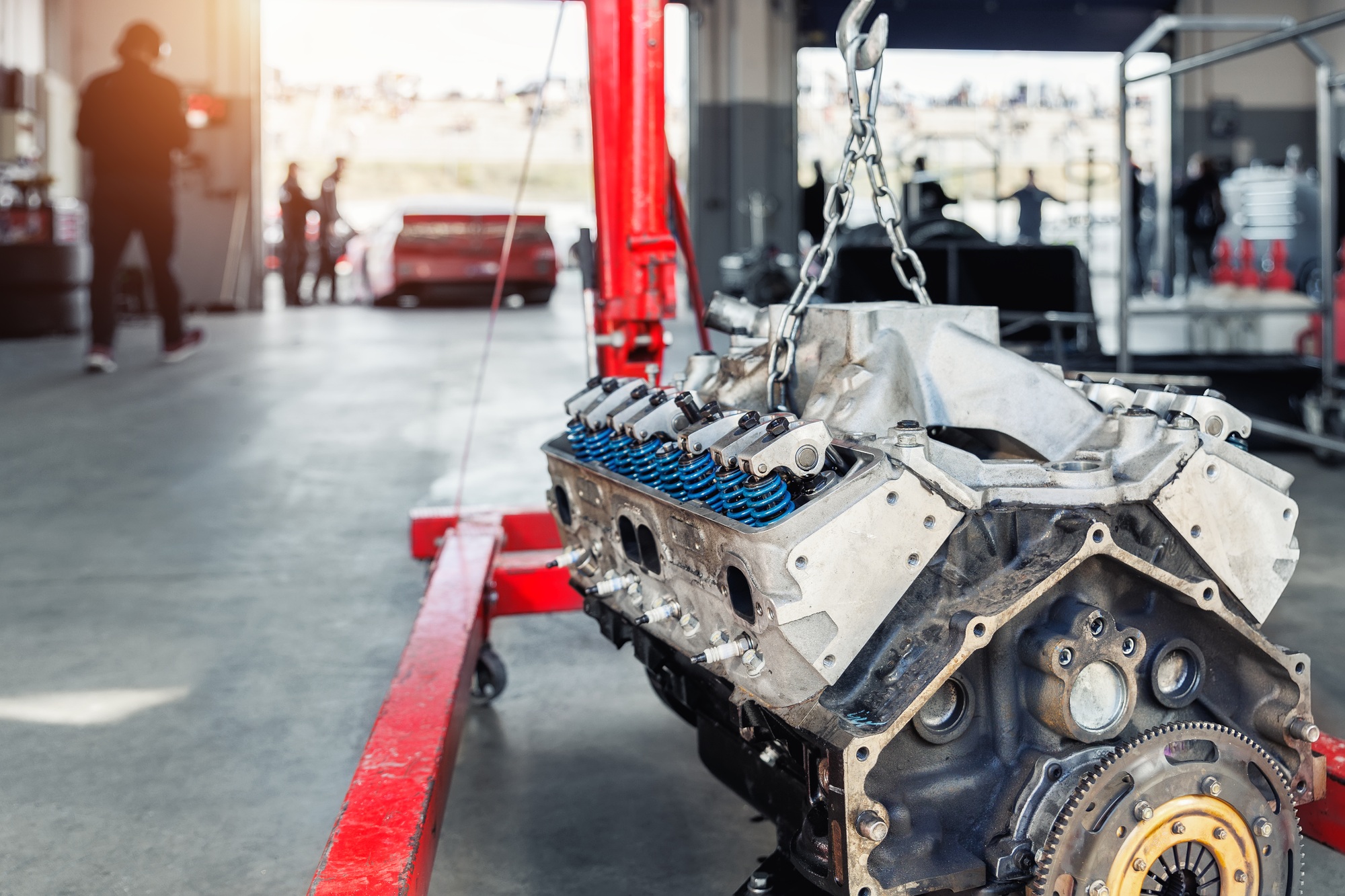 Motorsport pit lane garage box paddock hanged v8 engine suspended crane lift chain hook. Racing