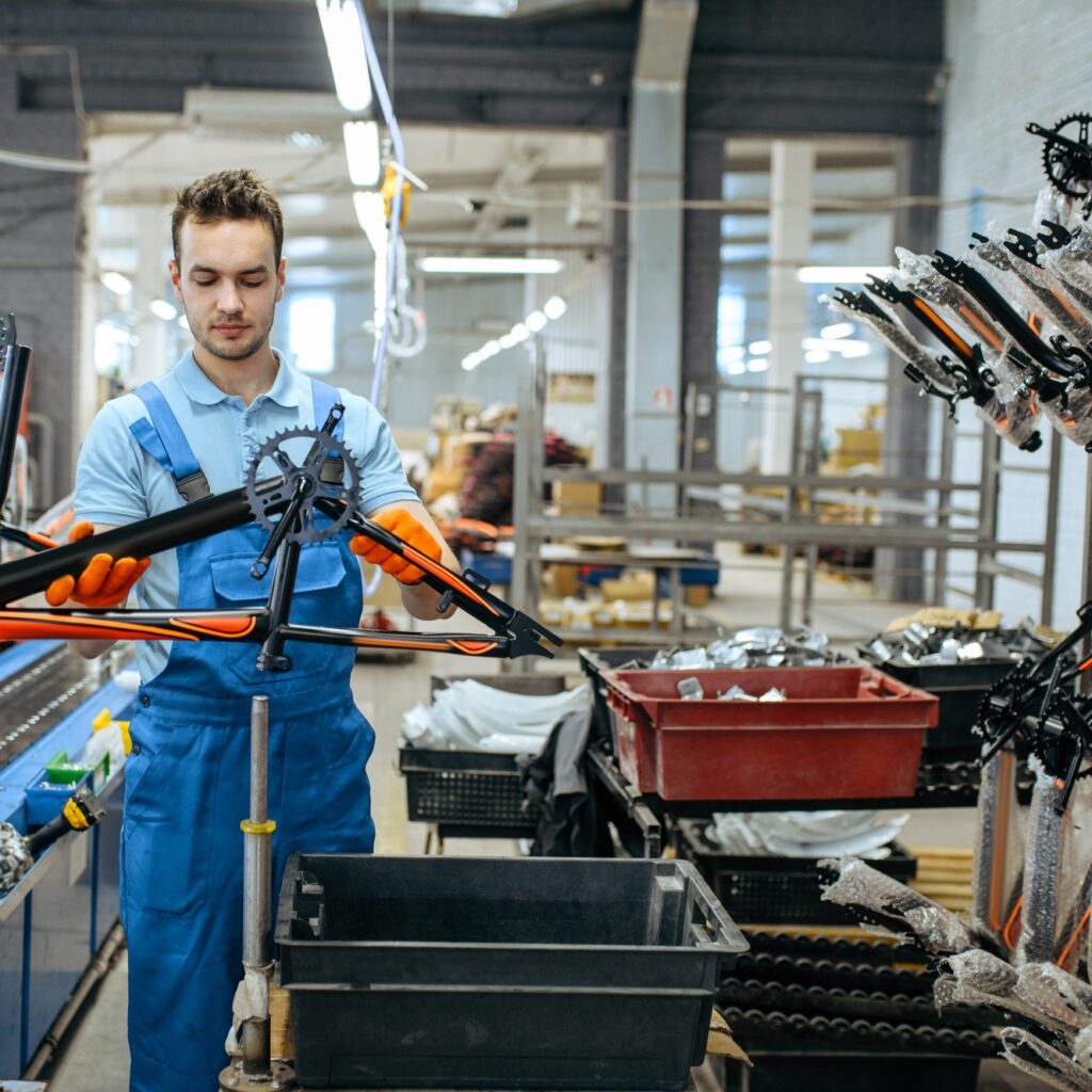 Bicycle factory, worker holds teen bike frame