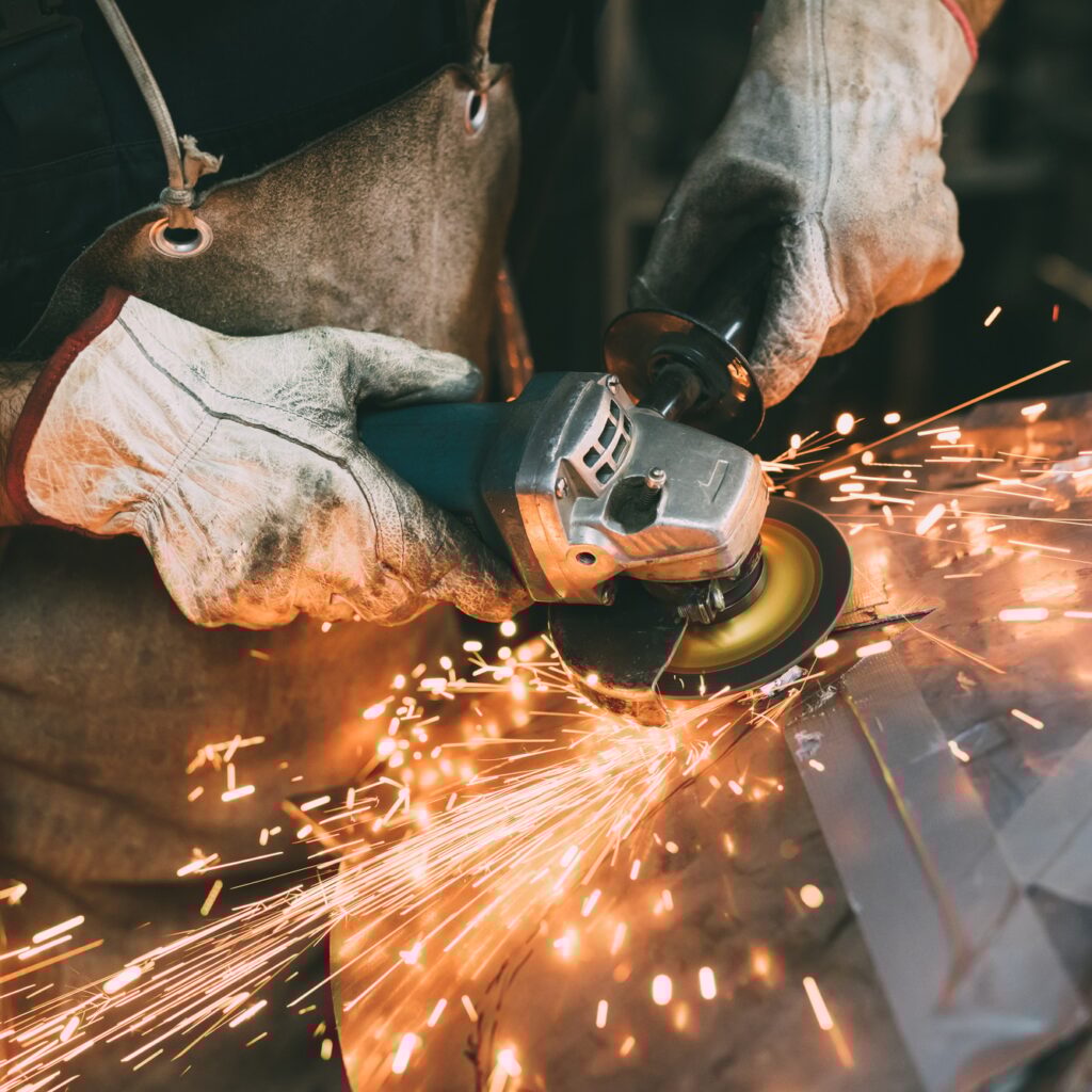 Hands of metalworker grinding copper in forge workshop